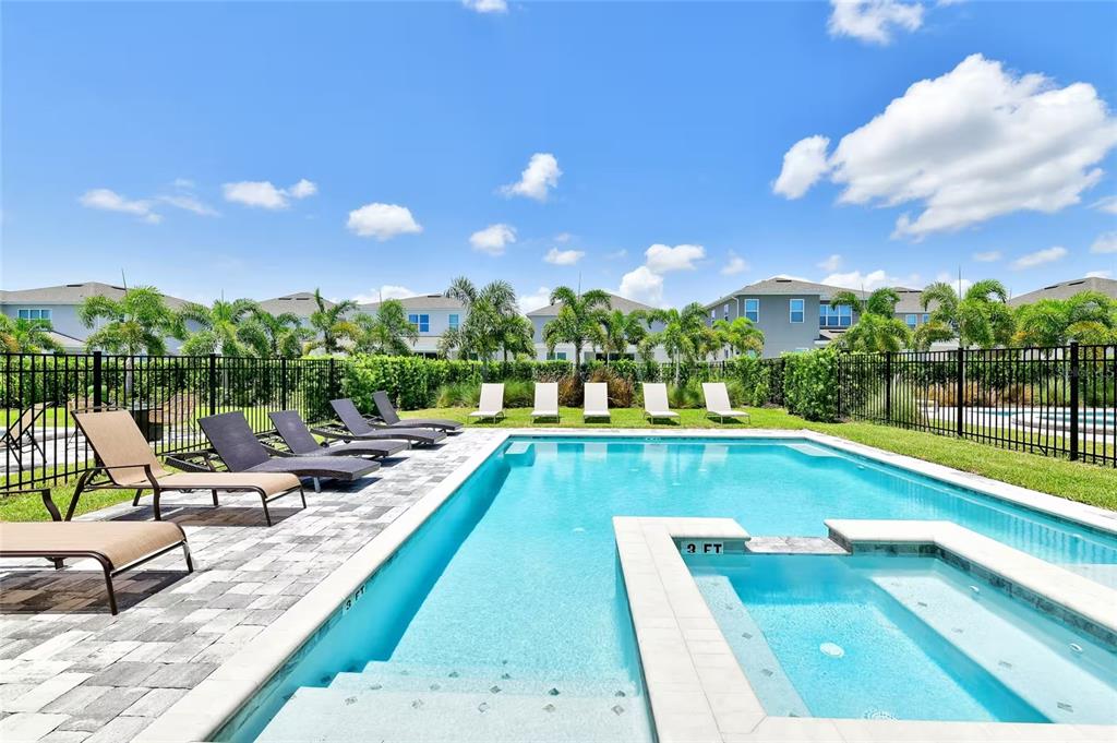 A swimming pool and hot tub are surrounded by lounge chairs and a black fence — 393 SOUTHFIELD STREET, KISSIMMEE, FL