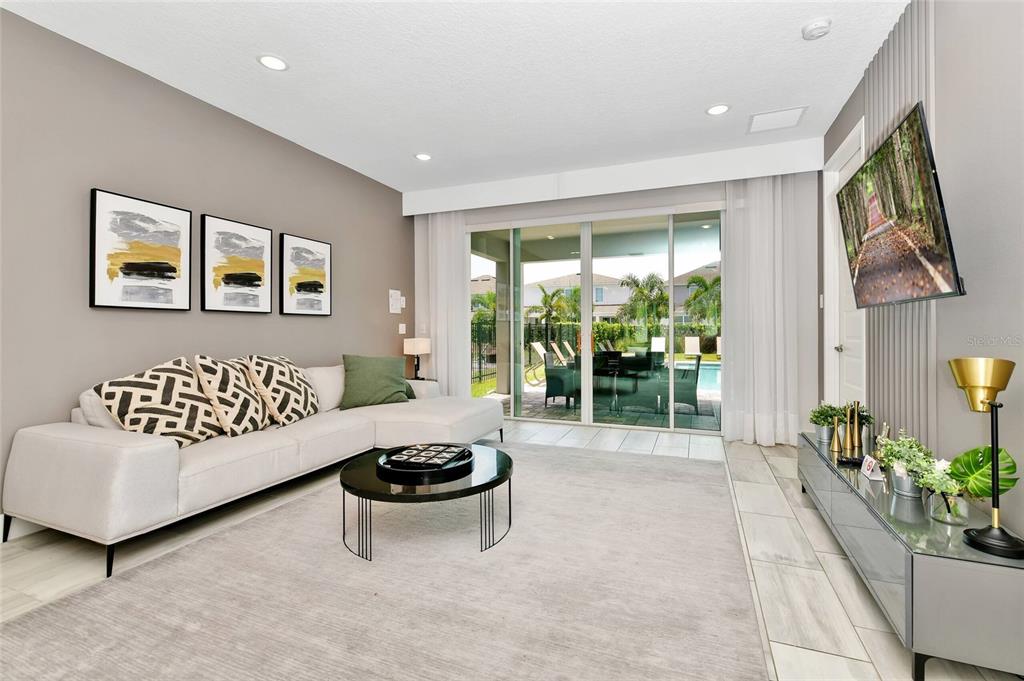 A modern living room features a white sectional sofa, a round coffee table, and sliding doors — 393 SOUTHFIELD STREET, KISSIMMEE, FL