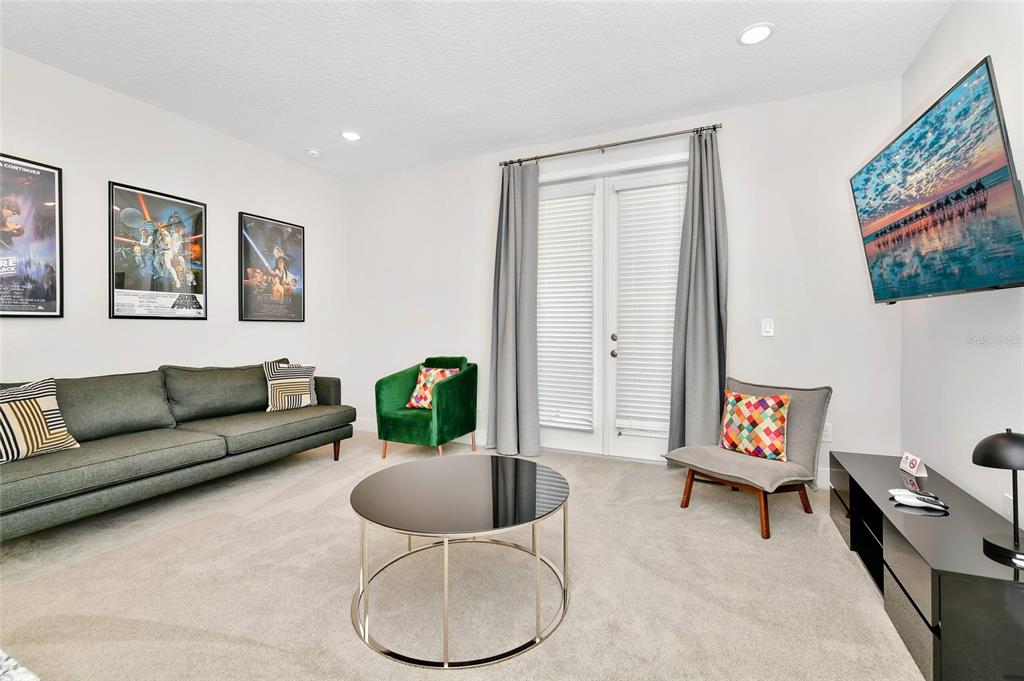 A living room features a grey sofa, a green armchair, a coffee table, and wall art — 393 SOUTHFIELD STREET, KISSIMMEE, FL