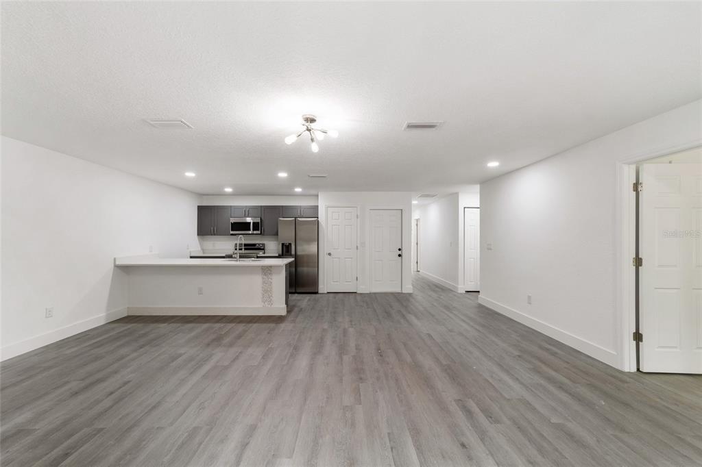 An open-concept living area features gray wood-look flooring, white walls, and a modern kitchen — 6845 SE 22ND AVENUE, OCALA, FL