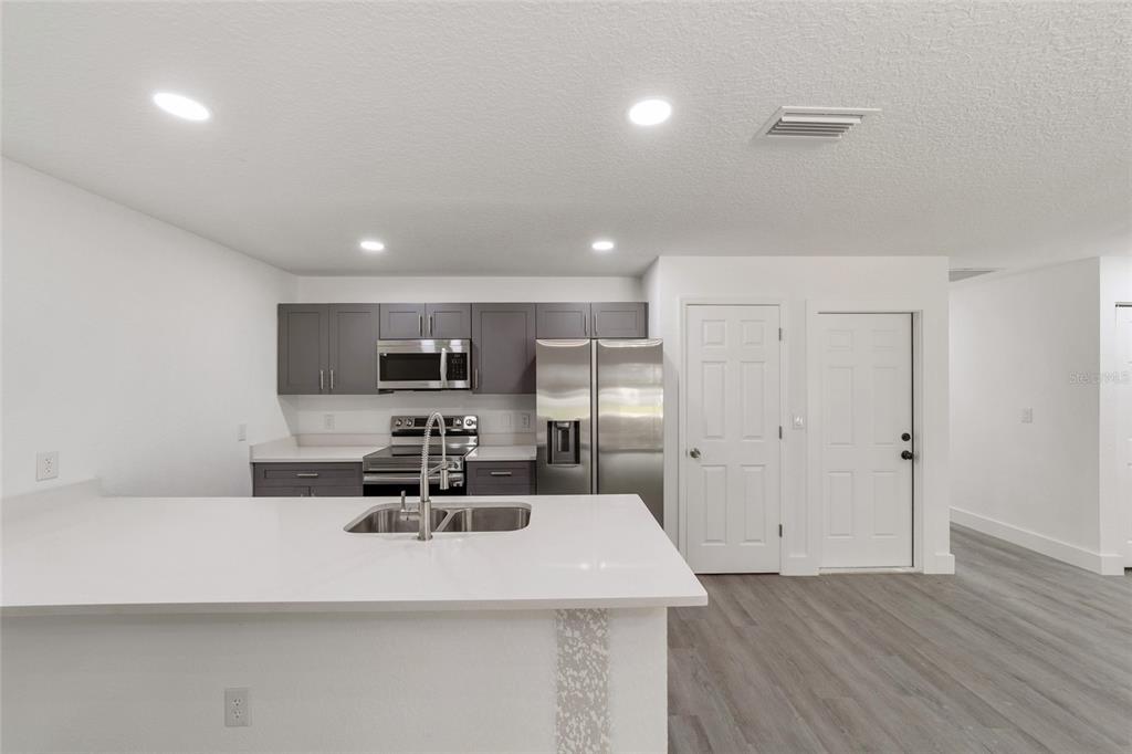 A modern kitchen features gray cabinets, stainless steel appliances, and a white quartz island countertop — 6845 SE 22ND AVENUE, OCALA, FL