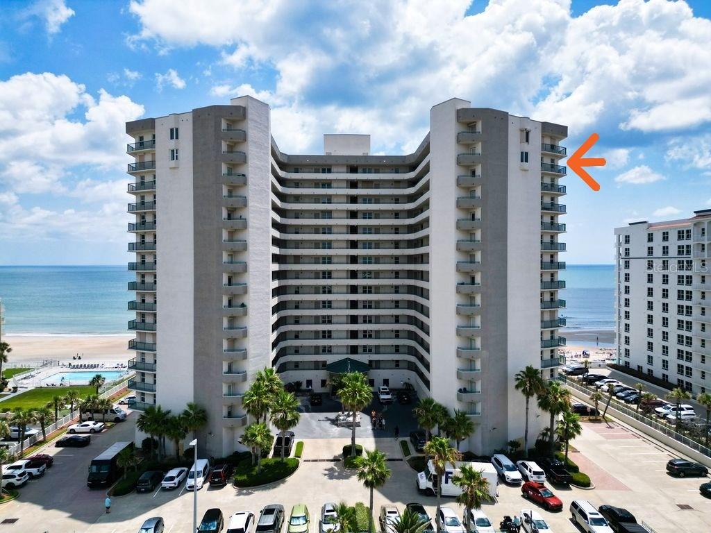 An exterior view of a high-rise beachfront condominium building with an orange arrow pointing upward — 2055 S ATLANTIC AVENUE UNIT 1410, DAYTONA BEACH, FL