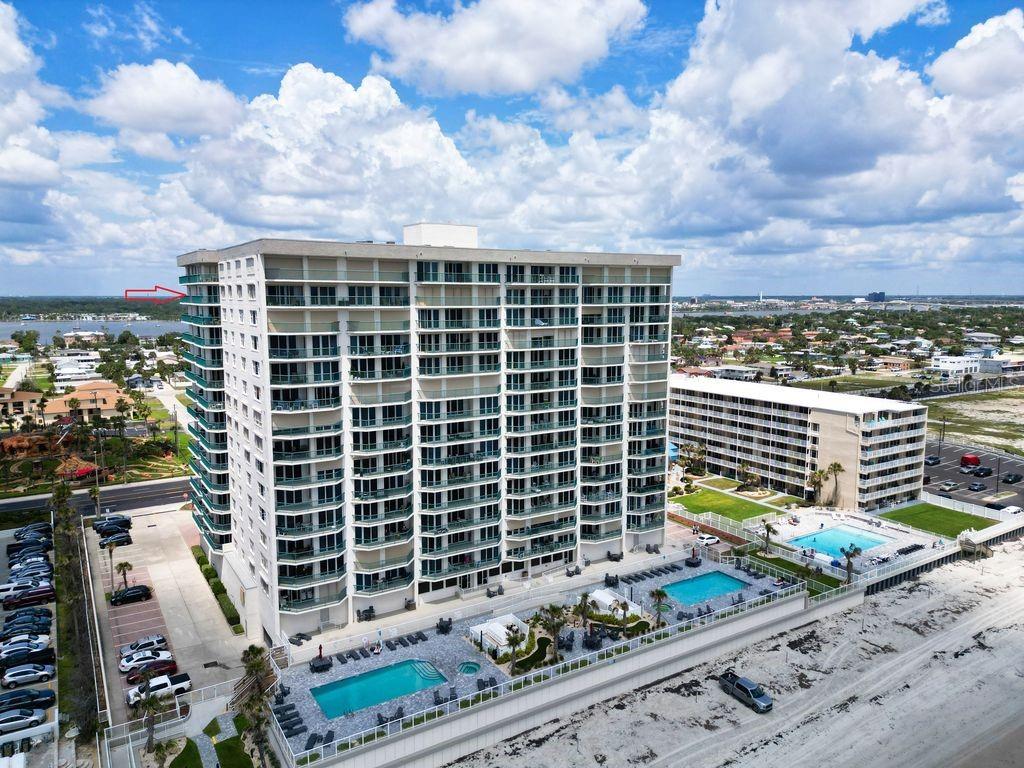 An aerial view of a tall beachfront condominium building with two swimming pools and parking — 2055 S ATLANTIC AVENUE UNIT 1410, DAYTONA BEACH, FL