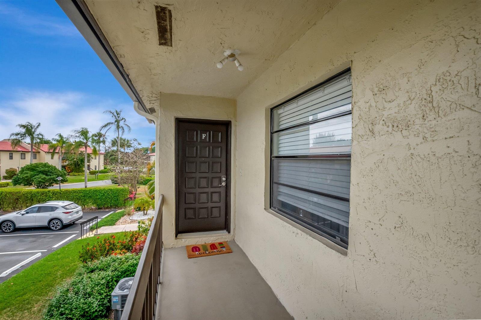 An exterior view of a covered apartment balcony with a brown door and a window — 21214 Lago Circle # 8f, Boca Raton FL 33433, BOCA RATON, FL