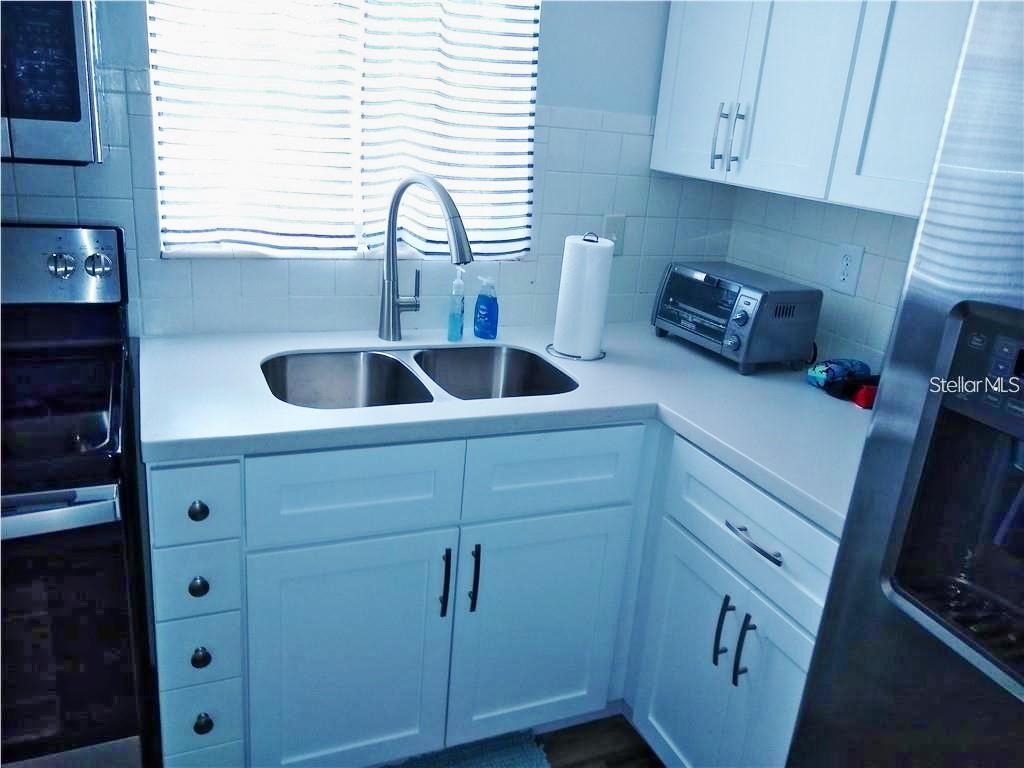 A kitchen features white cabinets, a stainless steel sink, and a toaster on the counter — 2531 FLAMINGO BOULEVARD UNIT L25, BRADENTON, FL