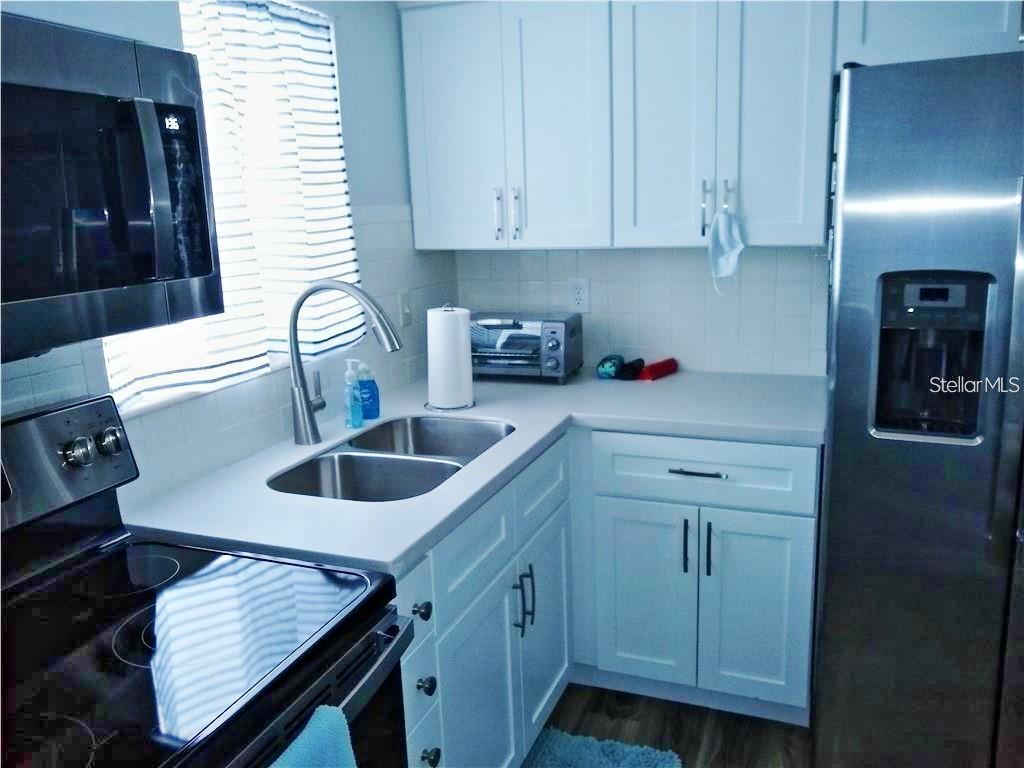 A kitchen features white cabinets, stainless steel appliances, a double sink, and light countertops — 2531 FLAMINGO BOULEVARD UNIT L25, BRADENTON, FL
