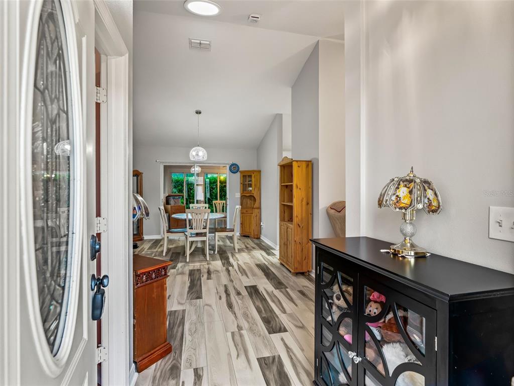 An entryway leads into a dining area with wood-look flooring and a glass sliding door — 17424 SE 111TH AVENUE, SUMMERFIELD, FL