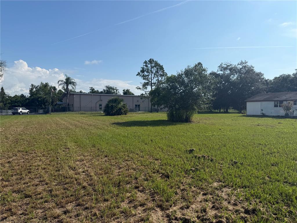 A grassy lot features a large metal building, a small house, and scattered trees — 904 N WALDRON STREET, ARCADIA, FL