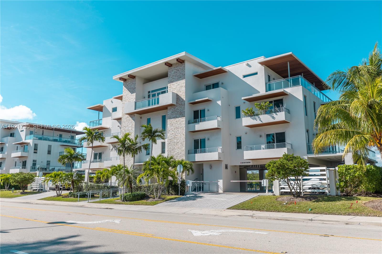 A multi-story modern apartment building with white stucco, stone accents, and balconies under a blue sky — 6100 N Ocean Dr # 3N, Hollywood FL 33019, HOLLYWOOD, FL