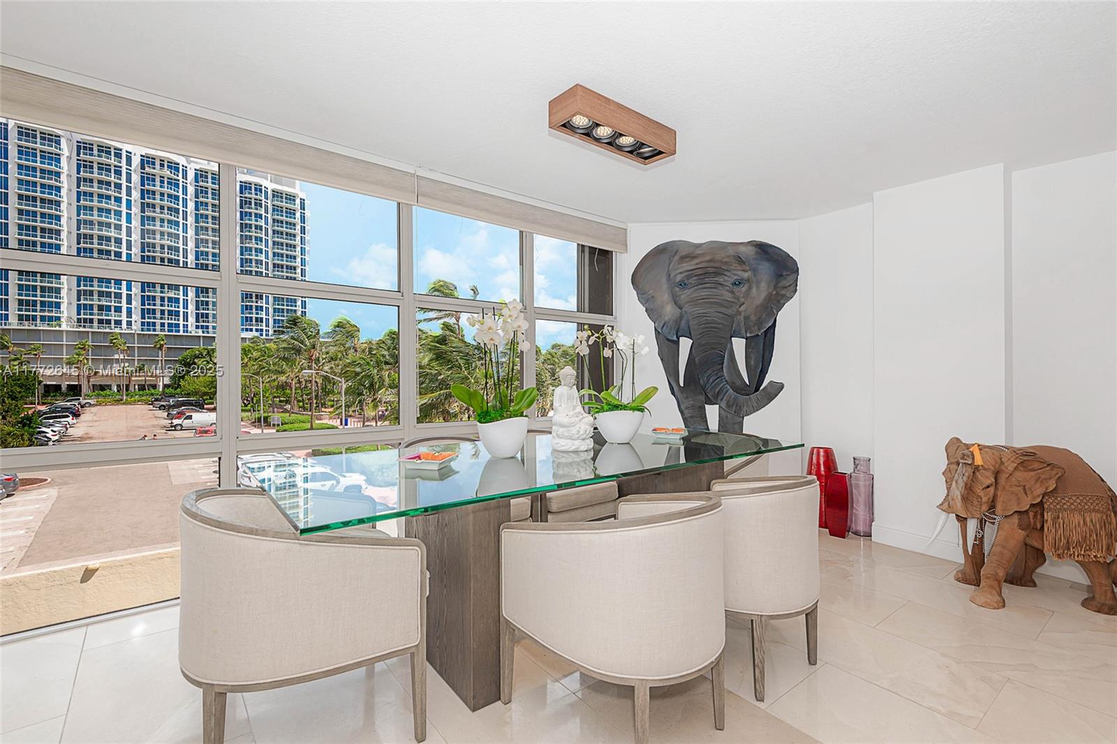 A dining room features a glass-topped table, upholstered chairs, and a large elephant wall mural — 6423 Collins Ave # 309, Miami Beach FL 33141, MIAMI BEACH, FL