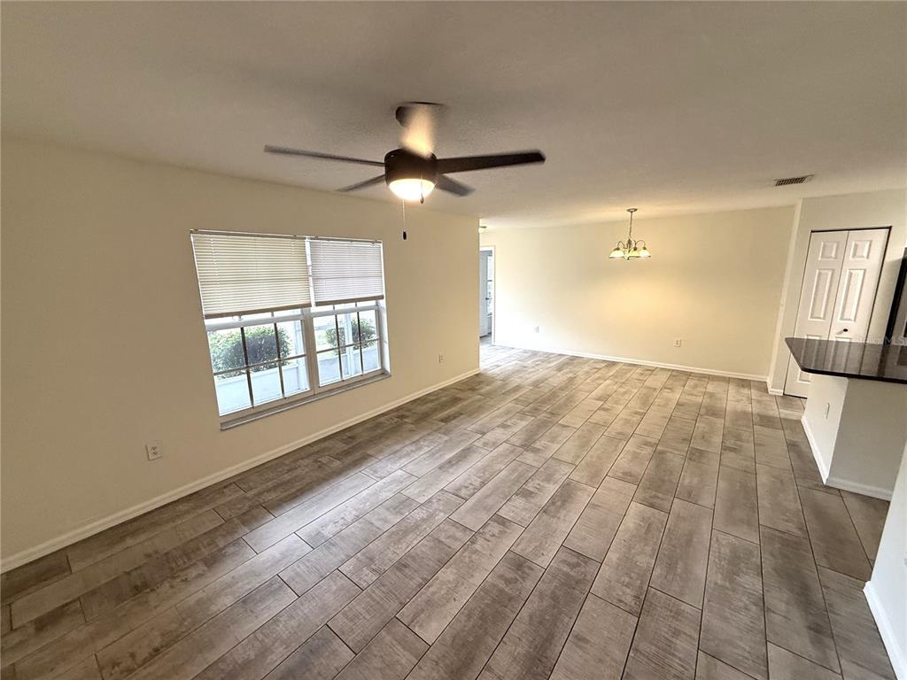 A living area with wood-look tile flooring, a ceiling fan, and a dining room chandelier — 10413 SUMMERVIEW CIRCLE, RIVERVIEW, FL
