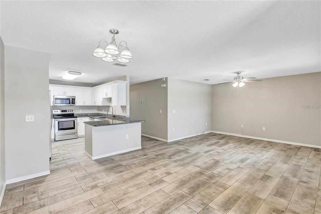 An open-concept kitchen with white cabinets and stainless steel appliances overlooks a spacious living area — 10413 SUMMERVIEW CIRCLE, RIVERVIEW, FL