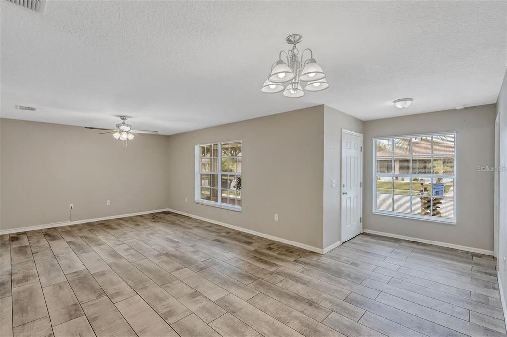 An empty room with light-colored walls, wood-look tile flooring, two windows, and two ceiling lights — 10413 SUMMERVIEW CIRCLE, RIVERVIEW, FL