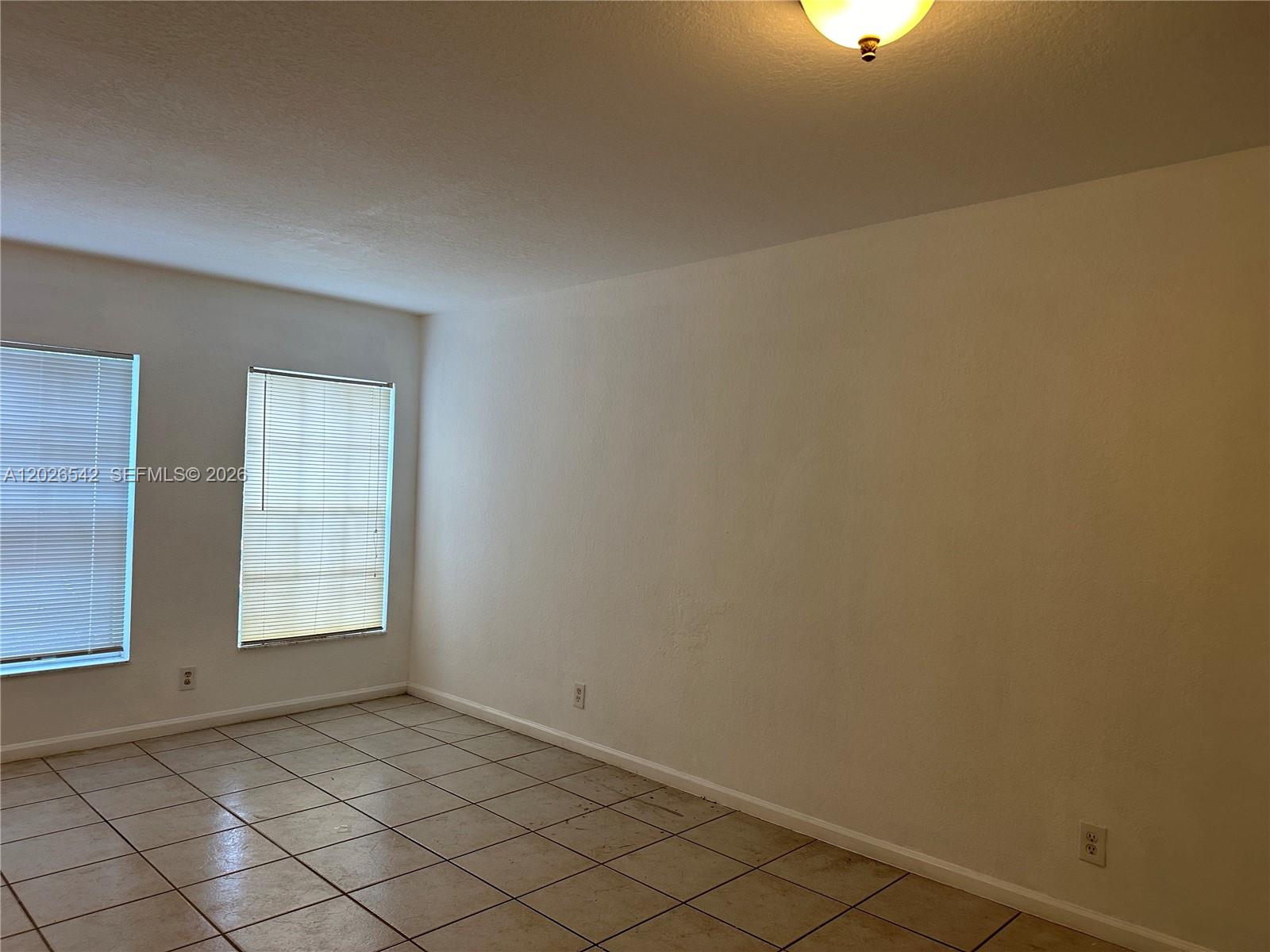An empty room features white walls, tiled flooring, two windows with blinds, and a ceiling light — 824 Summit Lake, West Palm Beach FL 33406, WEST PALM BEACH, FL