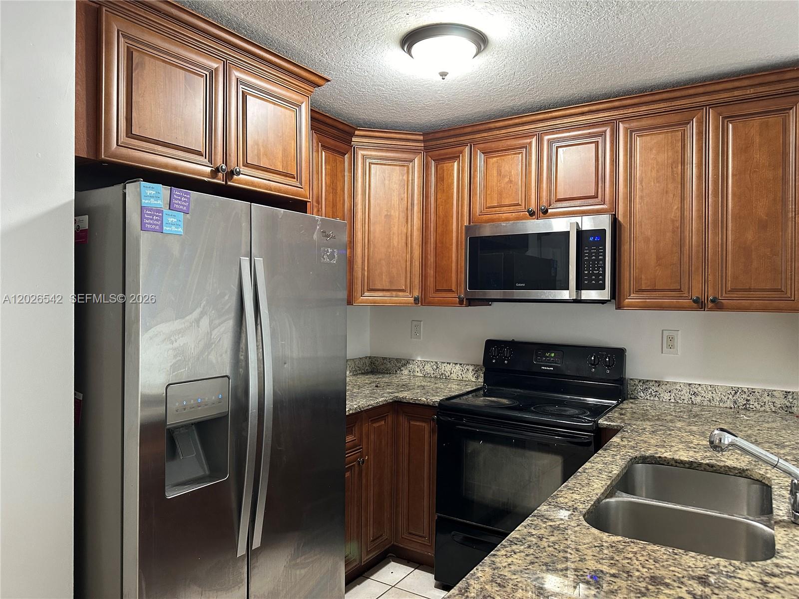 A kitchen features wood cabinets, granite countertops, stainless steel appliances, and a black stove — 824 Summit Lake, West Palm Beach FL 33406, WEST PALM BEACH, FL