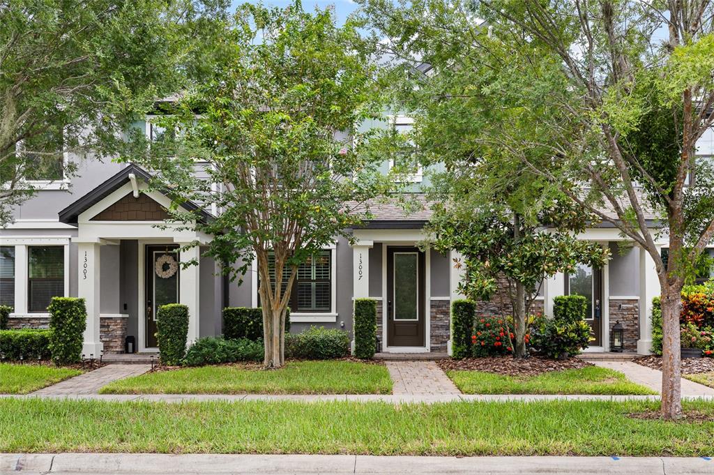 A row of three-story townhomes with gray siding, stone accents, and small front porches — 13007 BATTEN LANE, ODESSA, FL