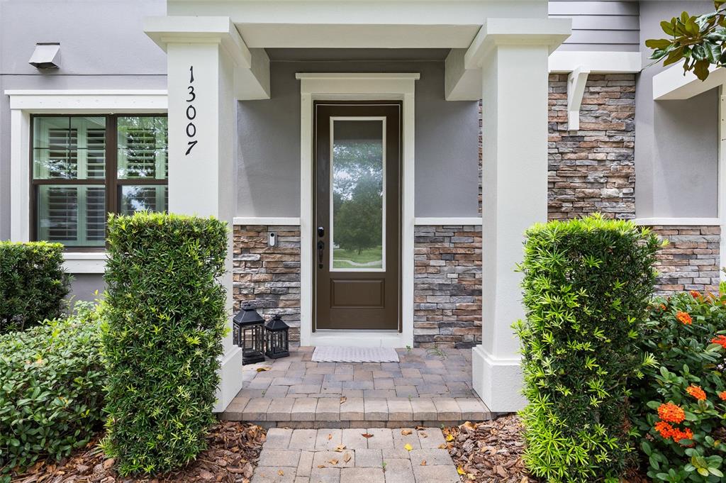 The front entrance features a brown door, stone veneer siding, and two white pillars — 13007 BATTEN LANE, ODESSA, FL