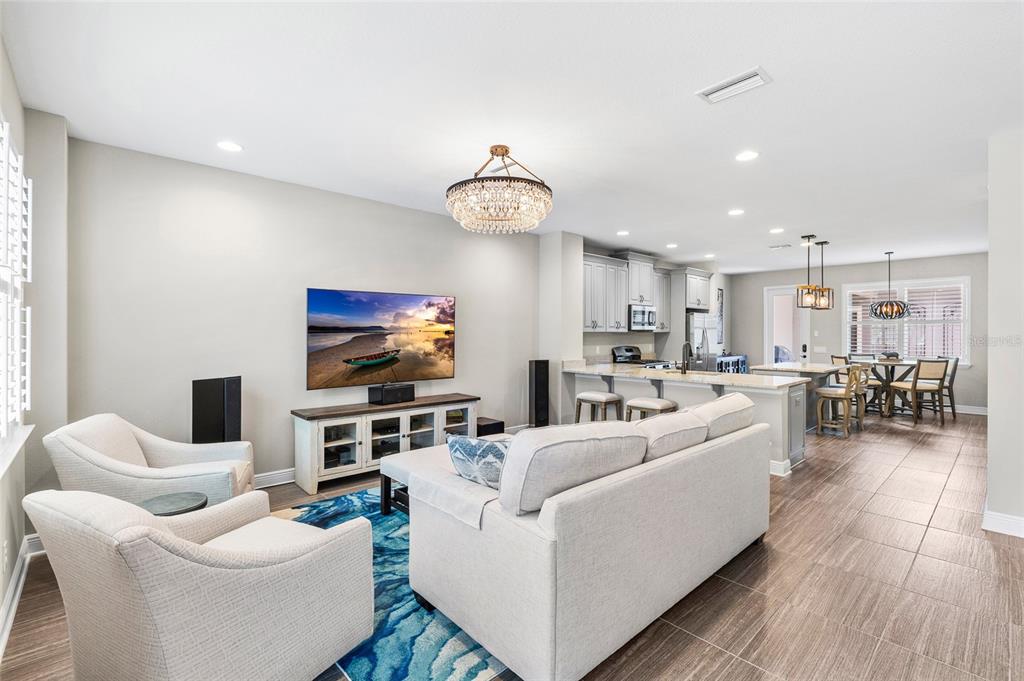 An open-concept living room and kitchen featuring a sofa, armchairs, and a large television — 13007 BATTEN LANE, ODESSA, FL