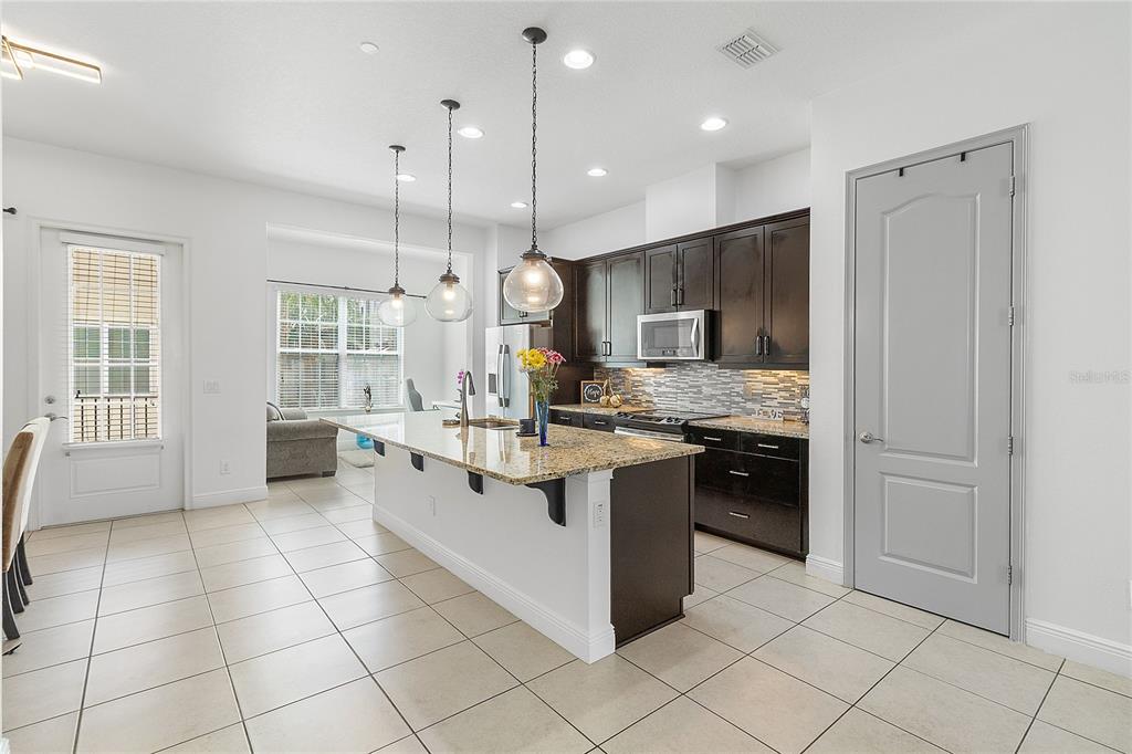 A bright living room features a large sectional sofa, a wooden media console, and tile flooring — 940 LOBELIA DRIVE, LAKE MARY, FL