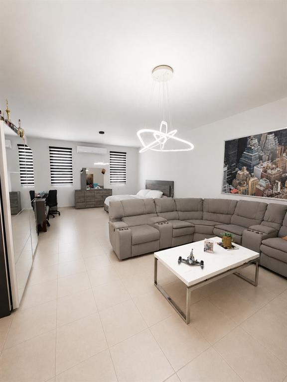 This open-concept bedroom features a large sectional sofa, a coffee table, and a modern chandelier — BO TALLABOA ALTA SOLAR 1 CARR 132 KM HM 16.3, PENUELAS, PR