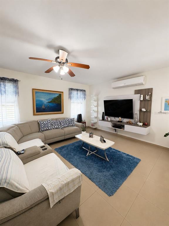 A living room features a sectional sofa, a blue area rug, and a wall-mounted television — BO TALLABOA ALTA SOLAR 1 CARR 132 KM HM 16.3, PENUELAS, PR
