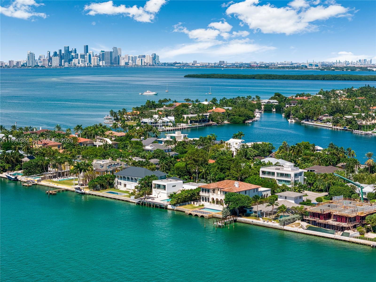 An aerial view shows luxury waterfront homes along a canal with the Miami skyline beyond — 640 S Mashta Dr, Key Biscayne FL 33149, KEY BISCAYNE, FL