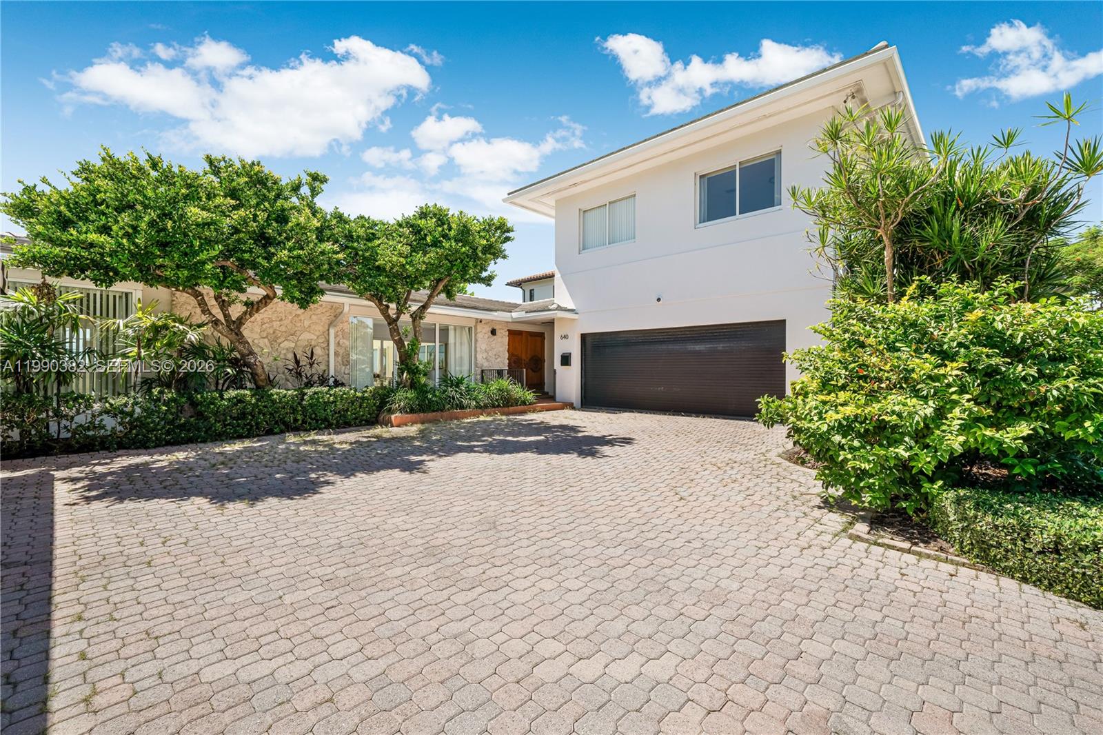 A two-story house with a stone facade, a paved driveway, and lush landscaping — 640 S Mashta Dr, Key Biscayne FL 33149, KEY BISCAYNE, FL