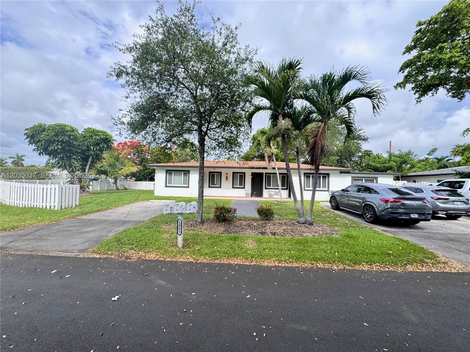 A single-story white house with a driveway, palm trees, and a front lawn — 1801 NE 25th Ave # 3, Pompano Beach FL 33062, POMPANO BEACH, FL