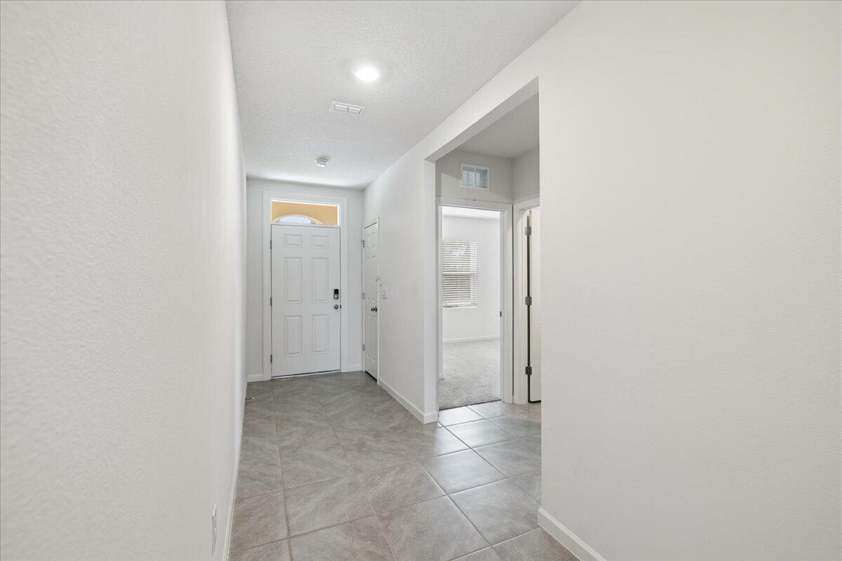 A tiled entryway leads to a white front door and a hallway with interior doors — 1072 Roseland Road, Sebastian FL 32958, SEBASTIAN, FL
