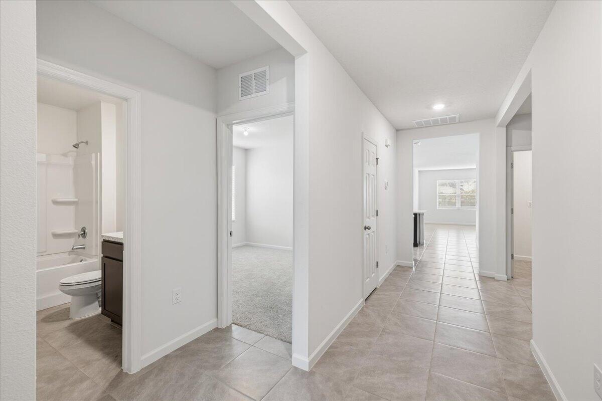 A hallway with tile flooring leads to a bedroom, a bathroom, and an open area — 1072 Roseland Road, Sebastian FL 32958, SEBASTIAN, FL