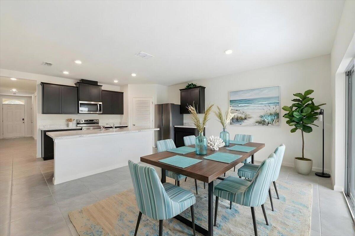 A modern kitchen with dark cabinets and a white island opens to a dining area — 1072 Roseland Road, Sebastian FL 32958, SEBASTIAN, FL