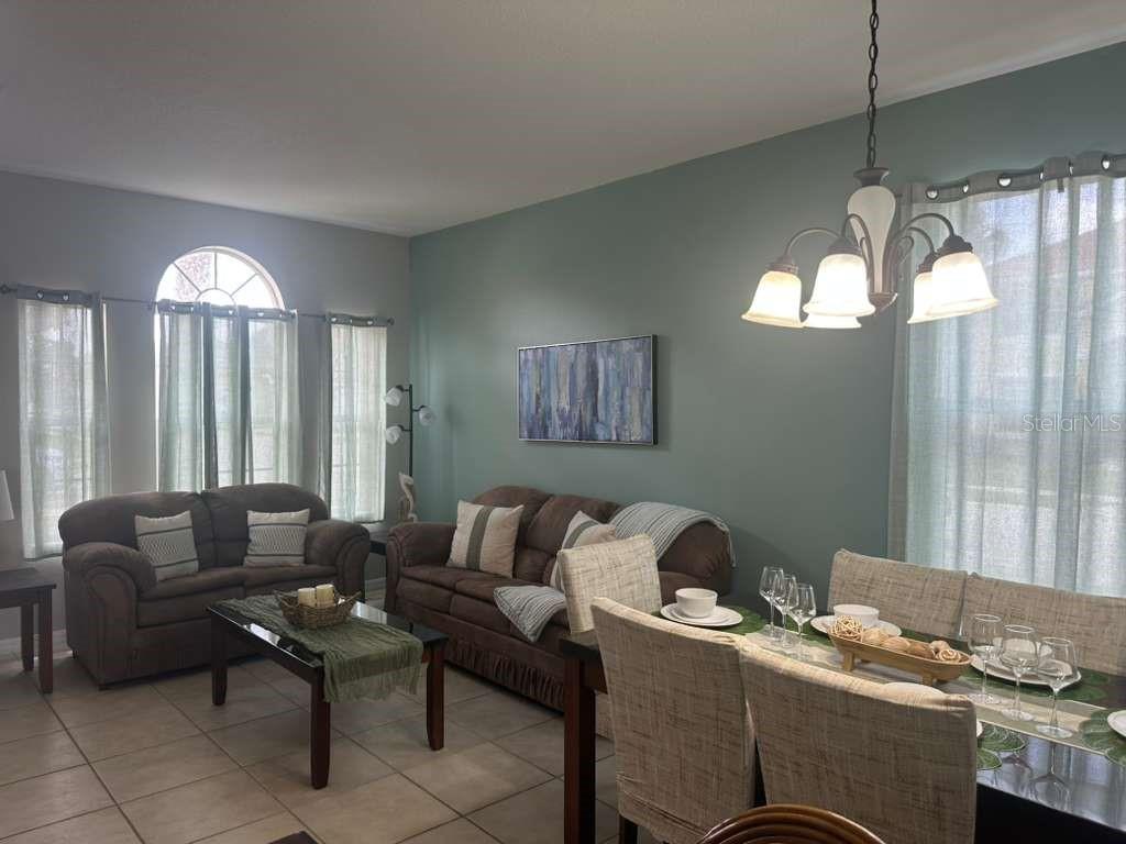 A living and dining area features tile floors, a teal accent wall, and neutral furniture — 109 MIRO DRIVE, DAVENPORT, FL