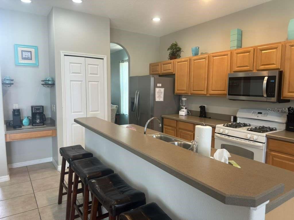A kitchen features light wood cabinets, a breakfast bar, and stainless steel appliances — 109 MIRO DRIVE, DAVENPORT, FL