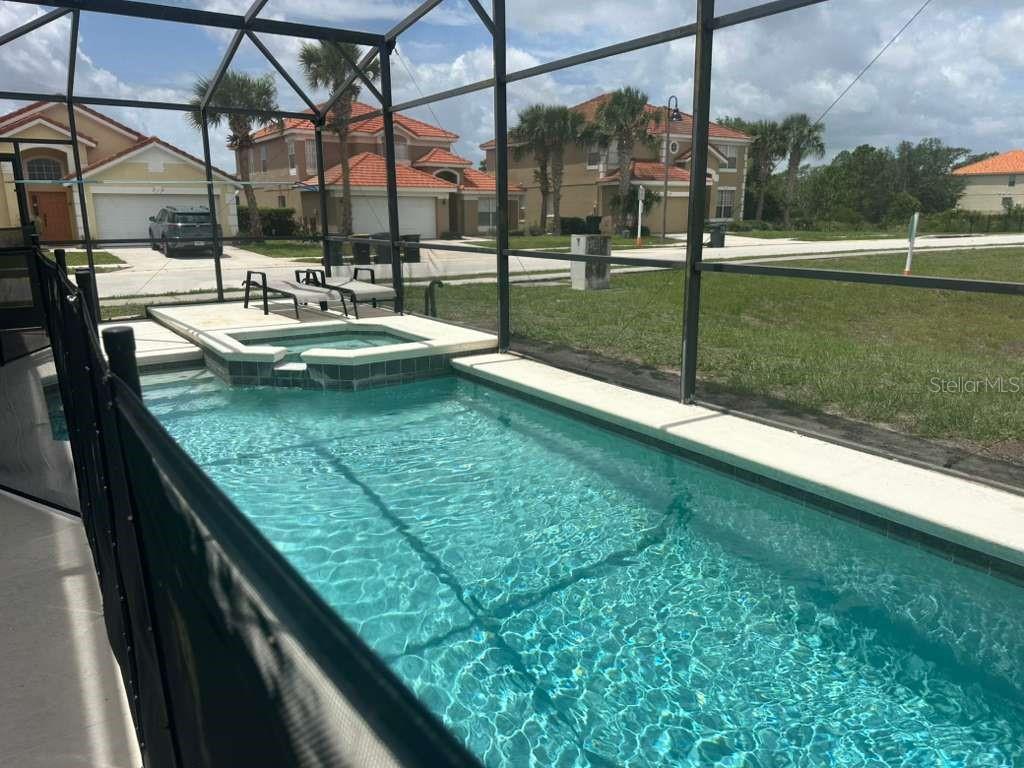A screened-in swimming pool and spa area with a view of neighboring houses — 109 MIRO DRIVE, DAVENPORT, FL