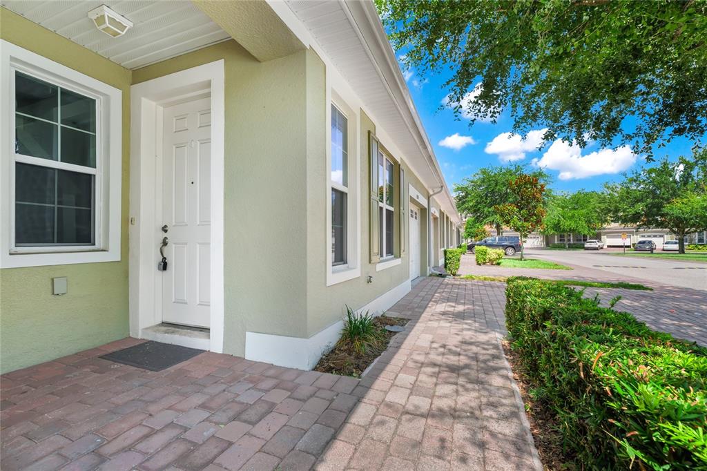A paved walkway leads to the front entrance of a light green stucco townhouse — 4824 POOLSIDE DRIVE, ST CLOUD, FL
