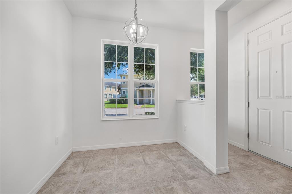 A bright dining area features tile flooring, a globe chandelier, and a large window — 4824 POOLSIDE DRIVE, ST CLOUD, FL