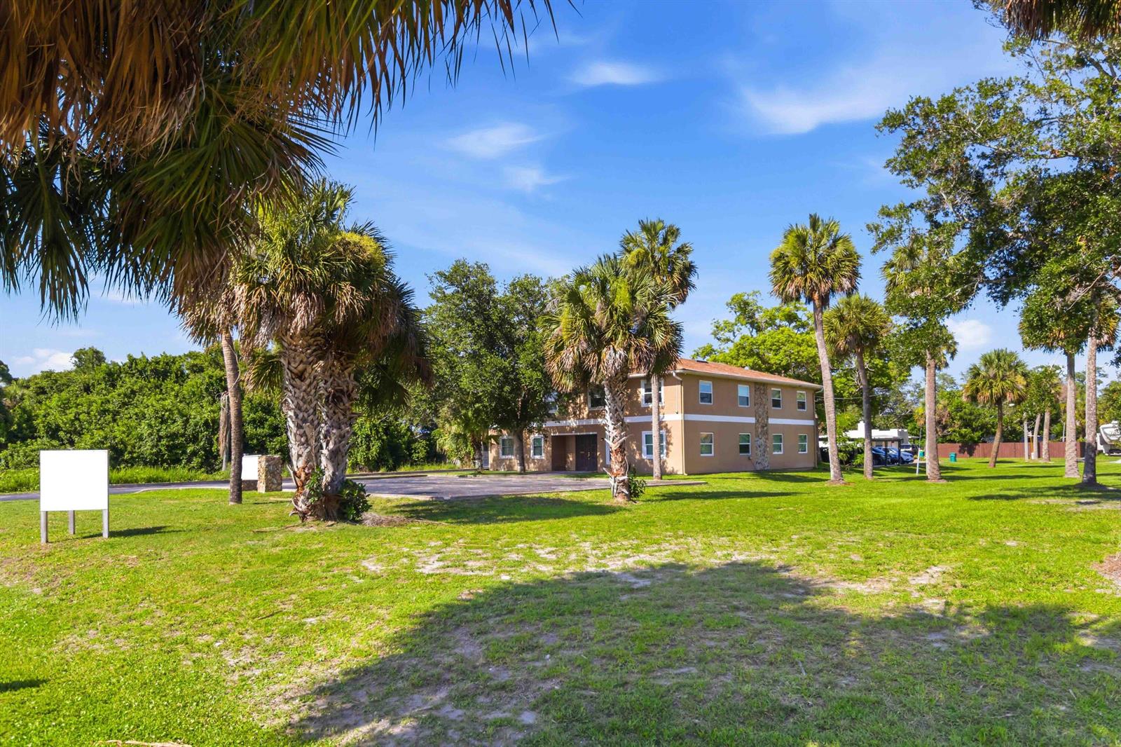 A two-story tan apartment building sits on a grassy lot with many palm trees — 111 Scott Street, Melbourne FL 32901, MELBOURNE, FL