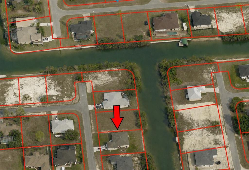 This aerial map shows residential lots and houses along a canal with a red arrow — 1911 NE 13TH AVENUE, CAPE CORAL, FL