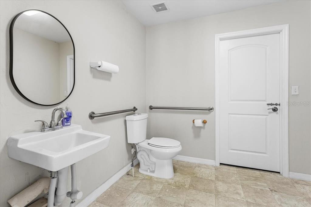 A bathroom features a wall-mounted sink, a toilet with grab bars, and a white door — 14827 MAIN STREET, ALACHUA, FL