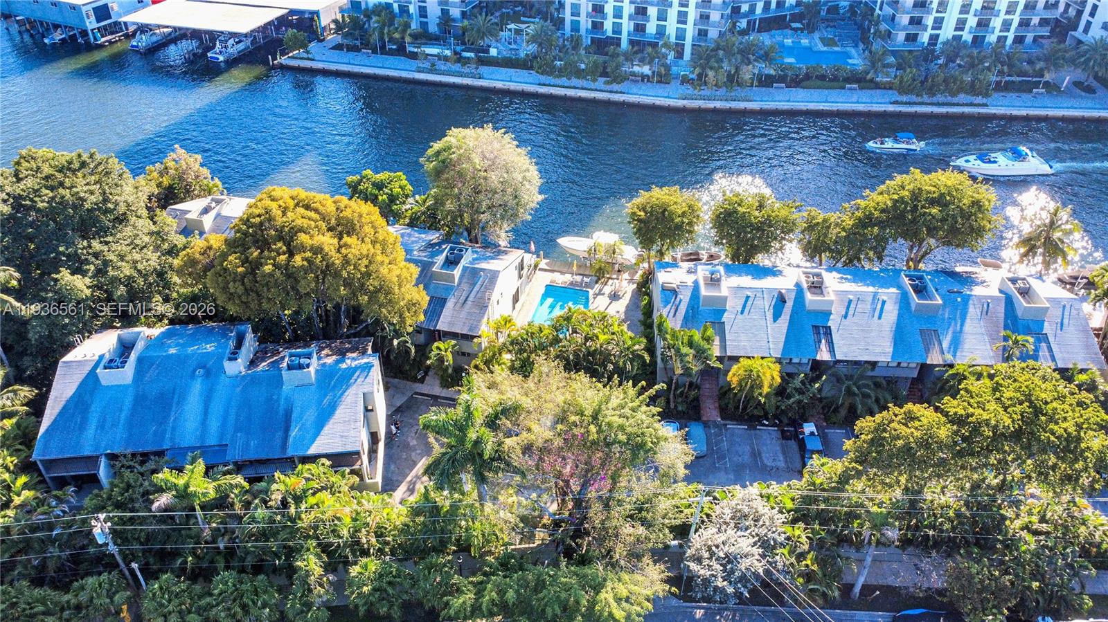 An aerial view shows townhouses with blue roofs, swimming pools, and boat docks along a canal — 1000 NW N River Dr # 20, Miami FL 33136, MIAMI, FL