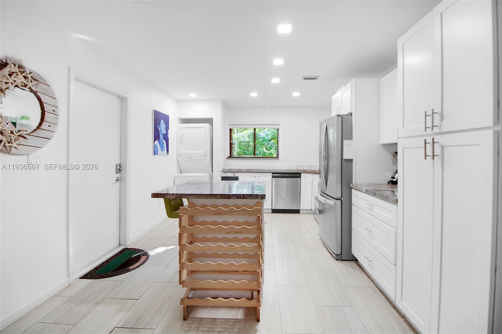 This kitchen features white cabinetry, stainless steel appliances, a granite-topped island, and light tile flooring — 1000 NW N River Dr # 20, Miami FL 33136, MIAMI, FL