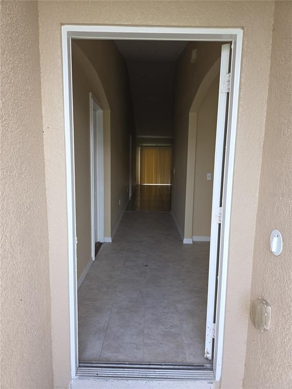 An open doorway leads into a tiled hallway with arched transitions and a distant window — 8 SAWFISH COURT, POINCIANA, FL