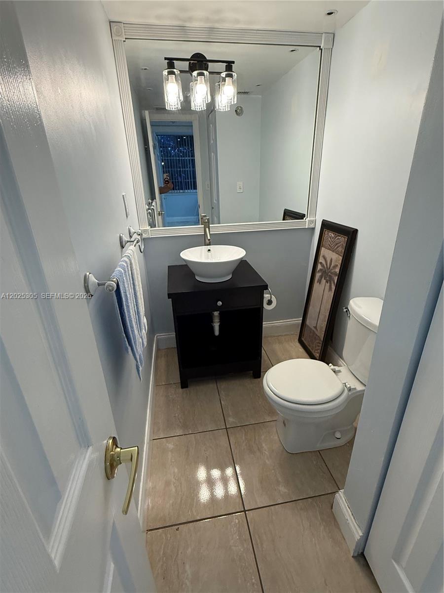 A small bathroom features a vessel sink vanity, a toilet, and a large wall mirror — 942 NE 199th St # 102, Miami FL 33179, MIAMI, FL