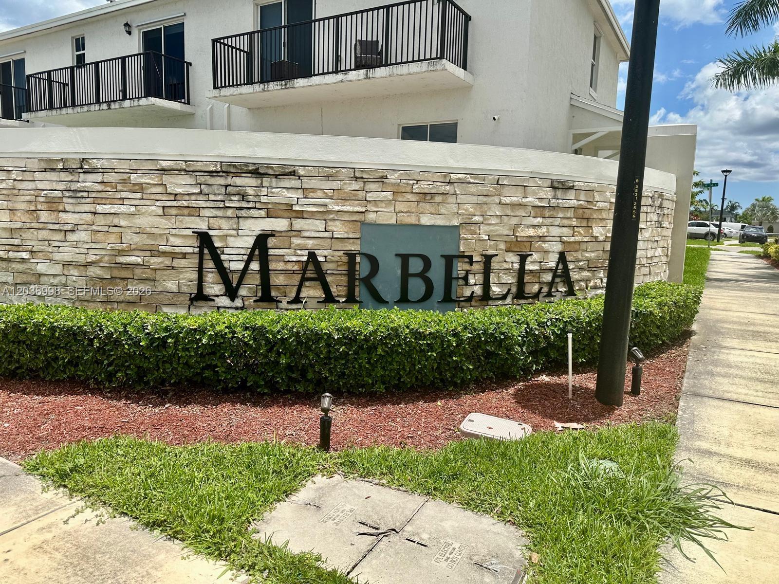 A stone wall with the name Marbella stands in front of a multi-story apartment building — 754 SE 19th St, Homestead FL 33034, HOMESTEAD, FL