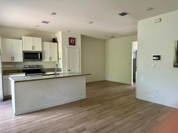 A kitchen with white cabinets and a center island opens to a living area — 754 SE 19th St, Homestead FL 33034, HOMESTEAD, FL