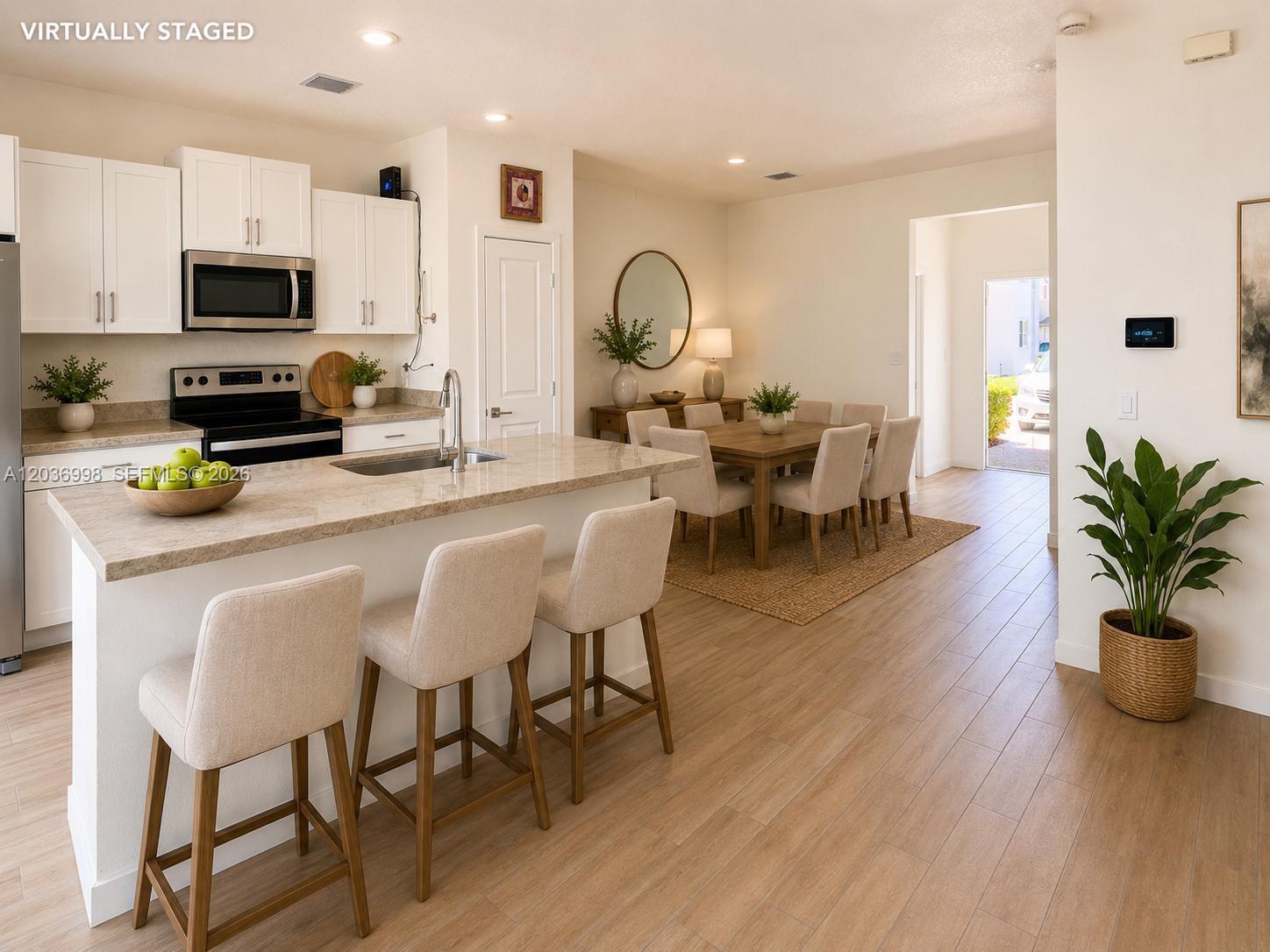 A kitchen with a granite island and bar stools overlooks a dining area — 754 SE 19th St, Homestead FL 33034, HOMESTEAD, FL