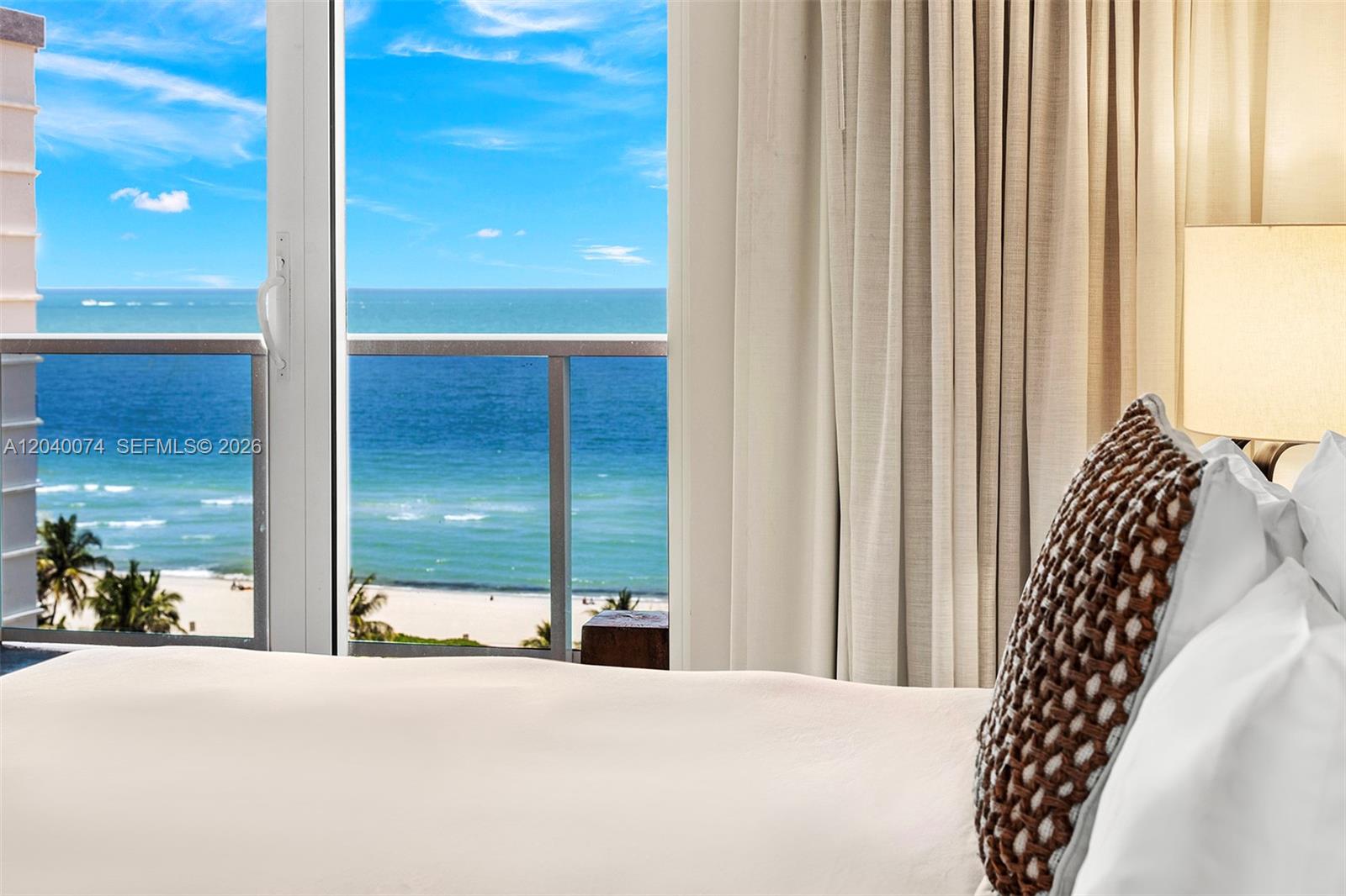 A bedroom view features a sliding glass door overlooking the ocean and sandy beach — 102 24 # 1222, Miami Beach FL 33139, MIAMI BEACH, FL