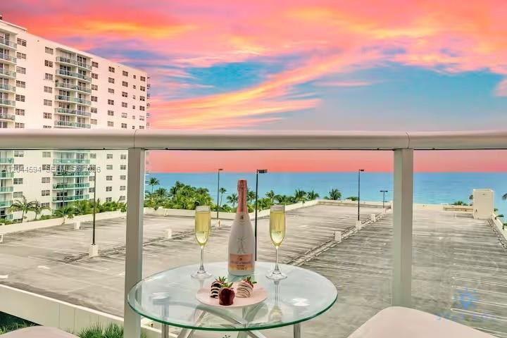 A balcony table with champagne and strawberries overlooks a parking lot and the ocean — 3901 S Ocean Dr # 6Y, Hollywood FL 33019, HOLLYWOOD, FL