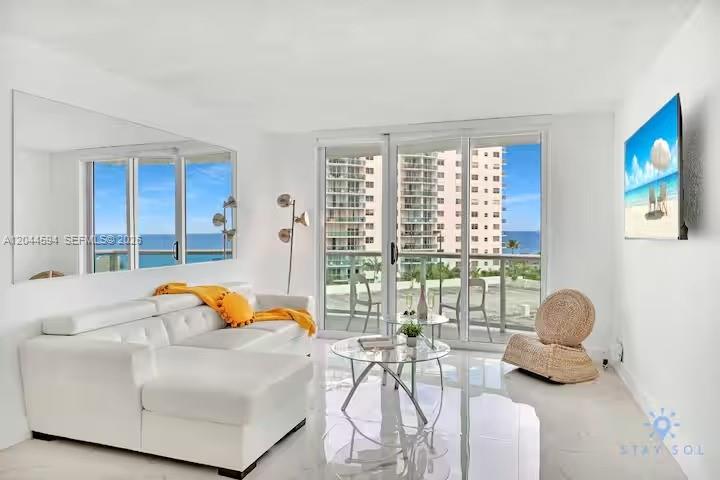 A bright living room features a white sectional sofa, glass coffee table, and ocean views — 3901 S Ocean Dr # 6Y, Hollywood FL 33019, HOLLYWOOD, FL