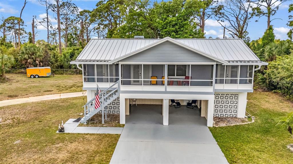 An elevated house with a metal roof, screened porch, and ground-level parking area — 3059 HOLCOMB ROAD, PORT CHARLOTTE, FL